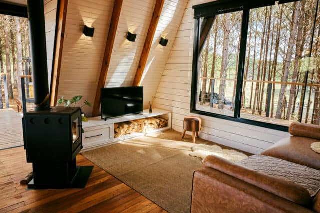 Intérieur d'un chalet ou d'une maison située en pleine nature, avec des baies vitrées laissant passer la lumière et une cheminée dans le salon - ArchiBienPensé, architecte d'intérieur à Annecy et en Haut-Savoie