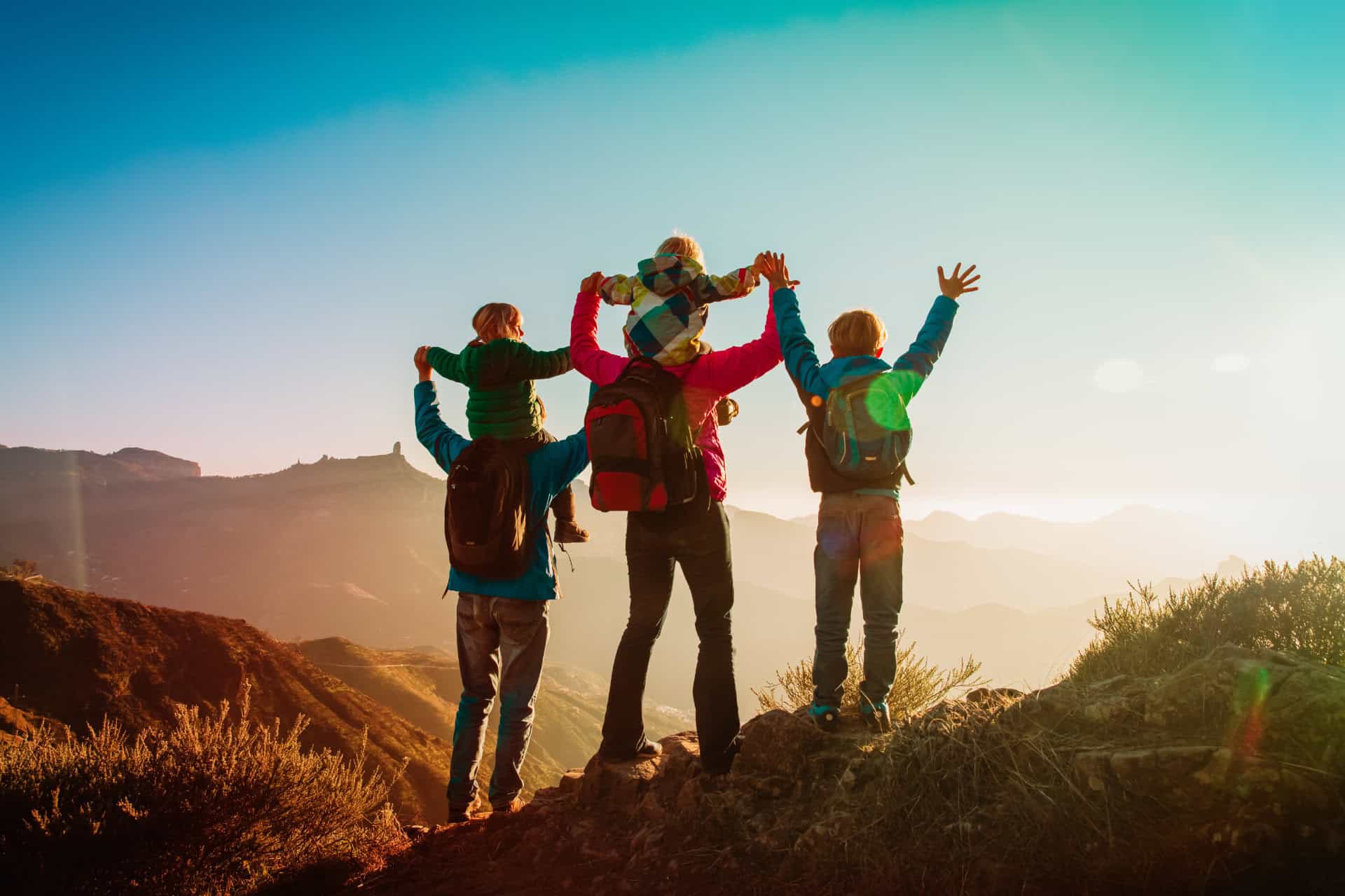 Une famille de 5 personnes face au soleil dans les montagnes